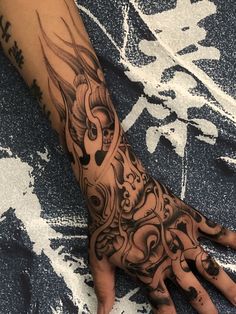 a person's hand with an intricate tattoo design on the left arm and wrist