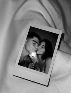 a black and white photo of two people laying on a bed with a light in their hand