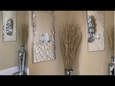 three mirrors are hanging on the wall above vases with dry grass in them and one is empty