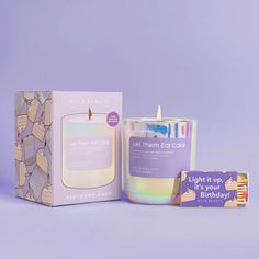 a lit candle next to a card and box on a purple background with the words light it up, it's your birthday