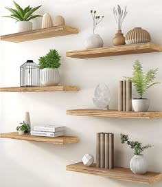 three wooden shelves with plants, books and vases on them against a white wall