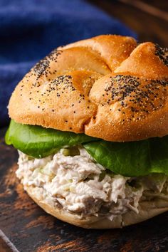 a chicken salad sandwich with lettuce and sesame seeds on a wooden table top