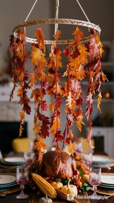 a table topped with a turkey under a chandelier filled with leaves and corn