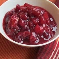 a white bowl filled with cranberry sauce on top of a red and white towel