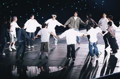 a group of young men standing on top of a stage holding onto each other's hands