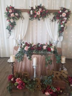 a table topped with flowers and candles next to a wall covered in lights at a wedding