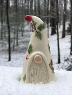 a ceramic gnome in the snow near some trees