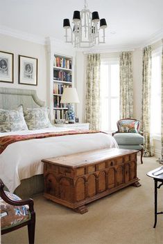 a bedroom with a bed, chair and bookshelf