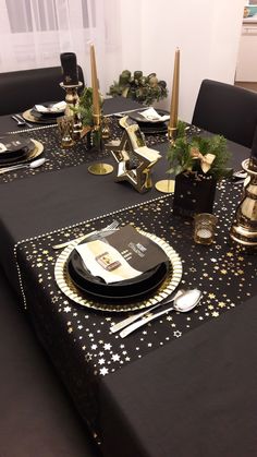 a black table cloth with gold stars on it and place settings in front of the table