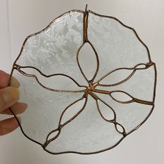 a hand holding a glass bowl with metal decoration