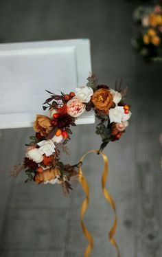 a wedding wreath with flowers and ribbons hanging from it's side on a chair