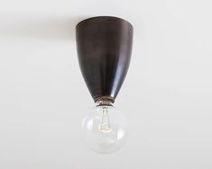 a light bulb hanging from the ceiling with a white wall in the backround