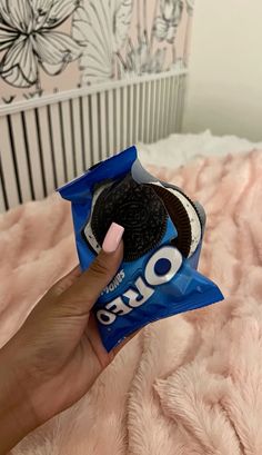 a person holding an oreo cookie in their hand on top of a pink blanket