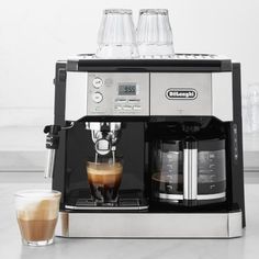 an espresso machine with two glasses next to it