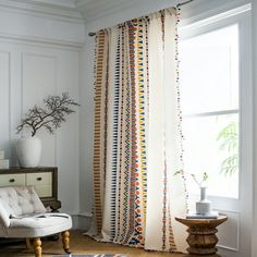 a white chair sitting in front of a window next to a rug on top of a hard wood floor