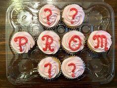 cupcakes with white frosting and red icing are arranged in a plastic tray