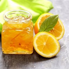 a glass jar filled with liquid next to sliced oranges and leaves on a table