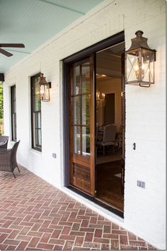 the front door to a house with brick flooring and glass doors that lead into an outdoor dining area