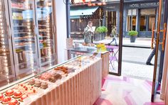 a display case filled with lots of donuts in front of a storefront window