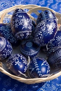 four decorated eggs sitting on top of a white tablecloth with blue and black designs