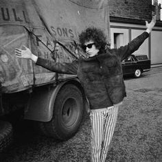 a man standing next to an airplane with the caption i'm bob dylan what?