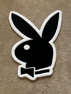 a black and white rabbit sticker sitting on top of a brown carpeted floor