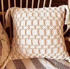 a white crocheted pillow sitting on top of a bed