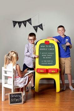 three children are playing with a chalkboard