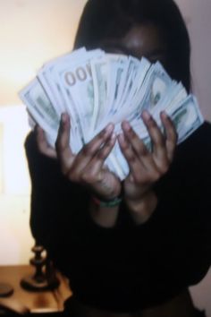 a woman is holding out her hands with money in front of her face and the light on behind her