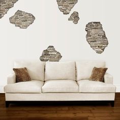 a white couch sitting in front of a wall with stone cutouts on it's sides