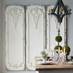 a dining room table is set with place settings and candles on the side, next to an ornate paneled wall