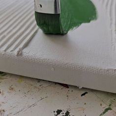 a green paint roller sitting on top of a piece of white paper that has been painted