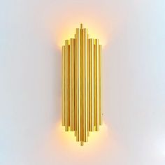 a wall light made out of gold sticks on a white background with the lights turned off