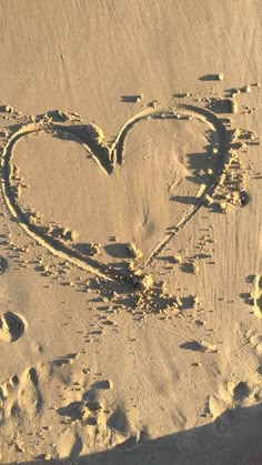 a heart drawn in the sand with footprints