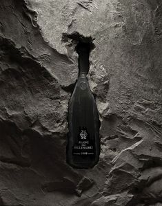 a bottle of wine sitting on top of a stone wall next to a black and white photo