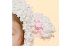 a baby wearing a knitted hat with pink and white balls on it's head