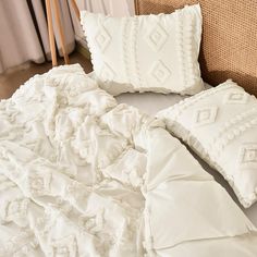 an unmade bed with white sheets and pillows