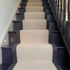 the stairs are lined with carpet and black railings, along with lights on either side