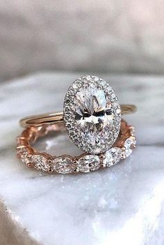 two wedding bands with an oval cut diamond in the center and side stones on each band