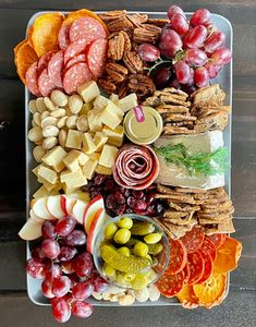 a platter filled with cheese, crackers, fruit and nuts