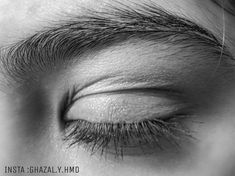 black and white photograph of an eye with long eyelashes, looking down at the camera