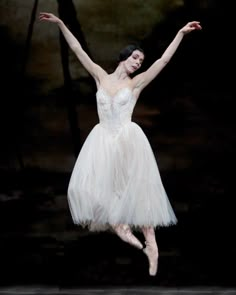 the ballerina is wearing a white tutu and holding her arms in the air