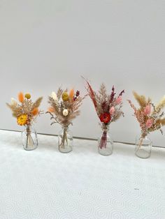 three glass vases with dried flowers in them