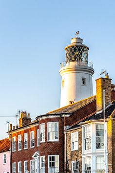 an old brick building with a white and black lighthouse on top in front of other buildings