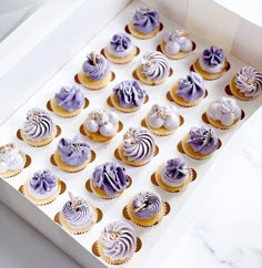 a box filled with cupcakes sitting on top of a white counter next to each other