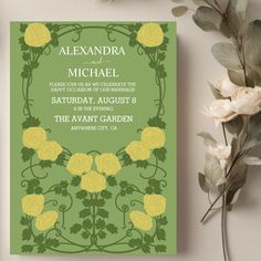 a green and yellow wedding card with roses on it, next to some white flowers