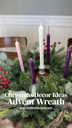 a christmas wreath with candles and greenery in it on top of a wooden table