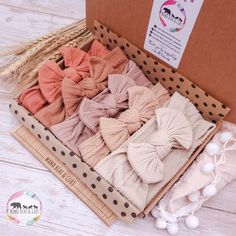 an open box filled with hair bows on top of a wooden floor next to pom poms