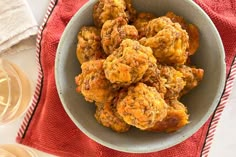 a bowl filled with fried food on top of a red towel next to wine glasses