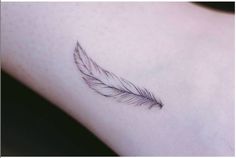 a small feather tattoo on the left side of the arm is shown in black and white